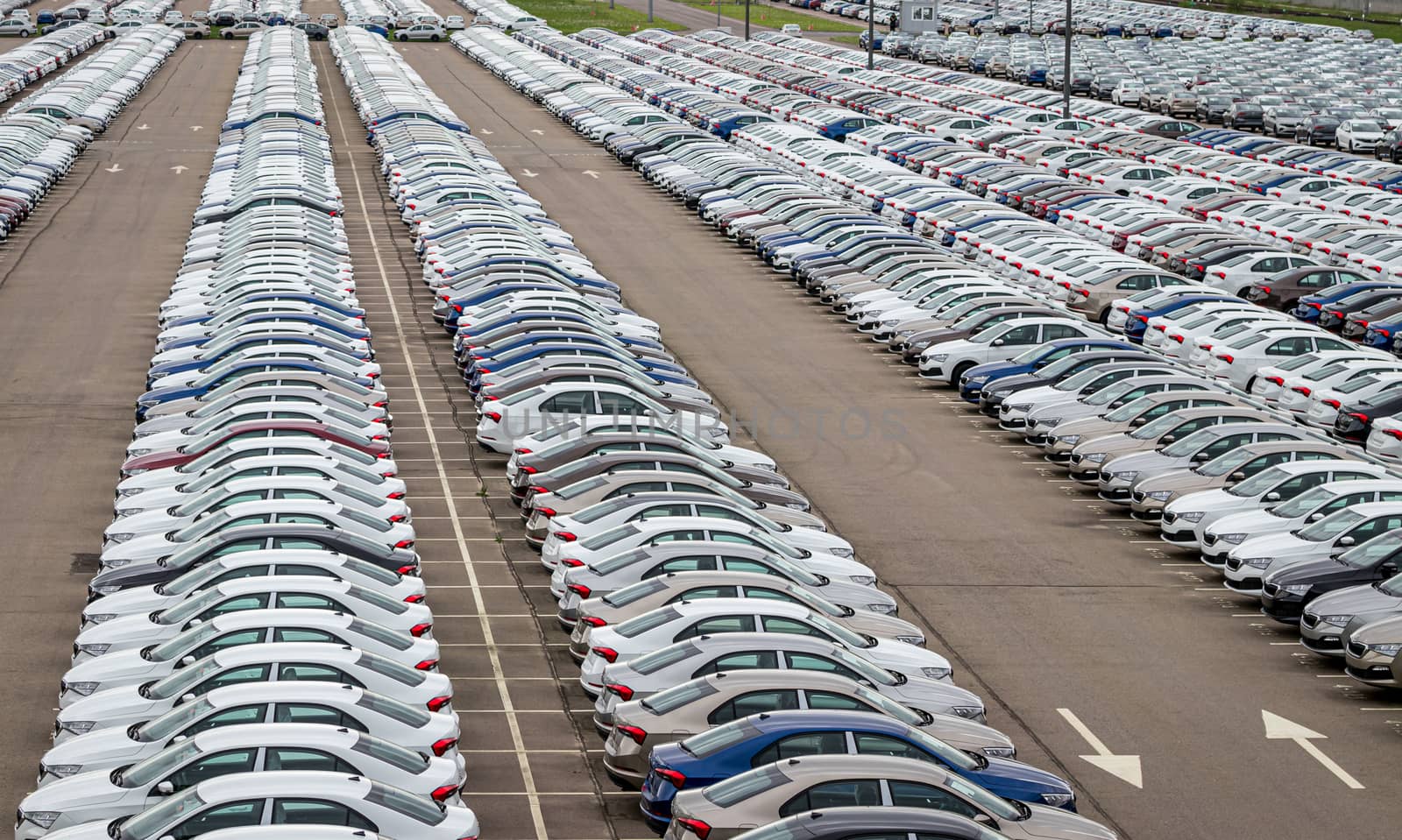 Rows of a new cars parked in a distribution center of a car factory. Top view to the parking in the open air. by Eugene_Yemelyanov