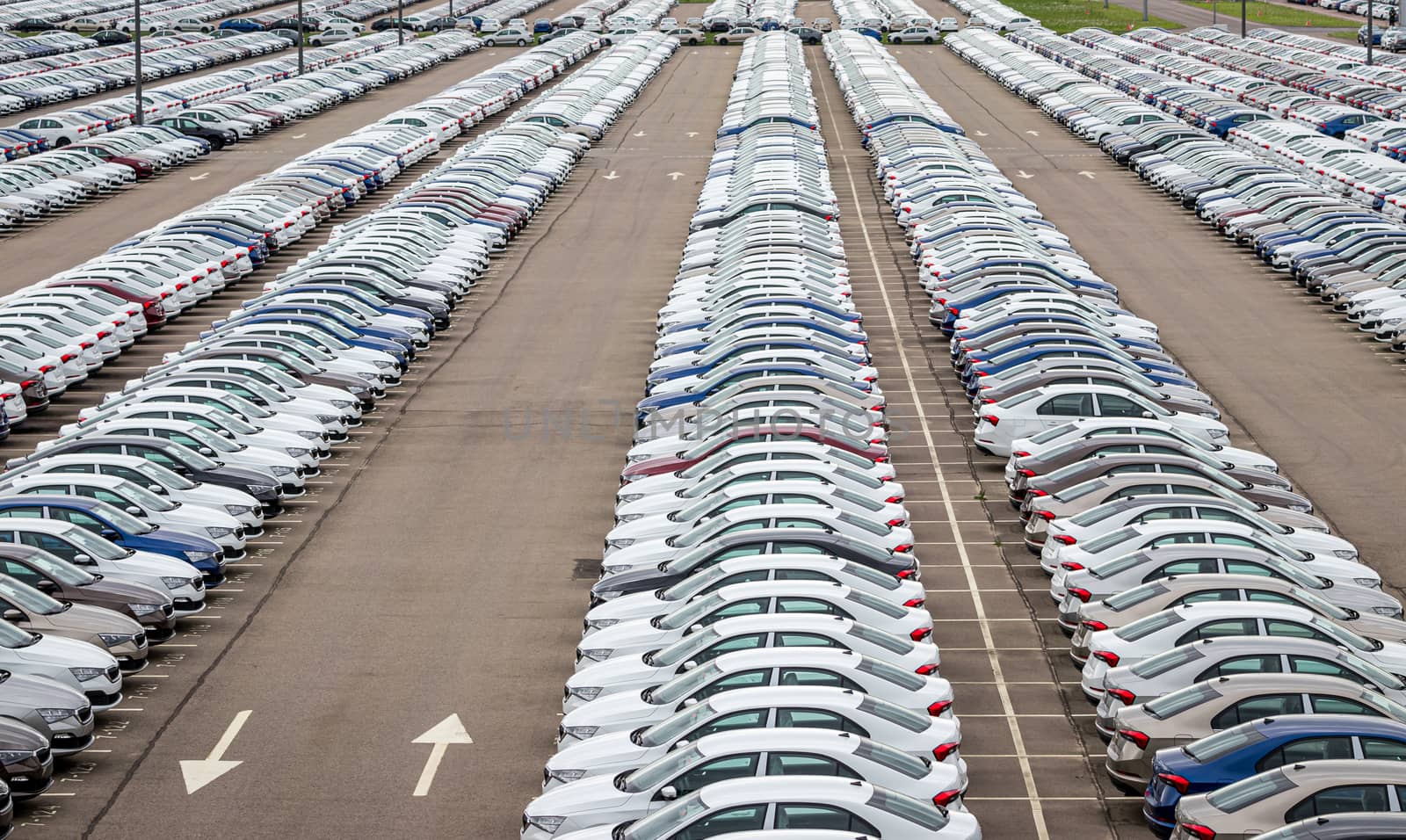 Rows of a new cars parked in a distribution center of a car factory. Top view to the parking in the open air.