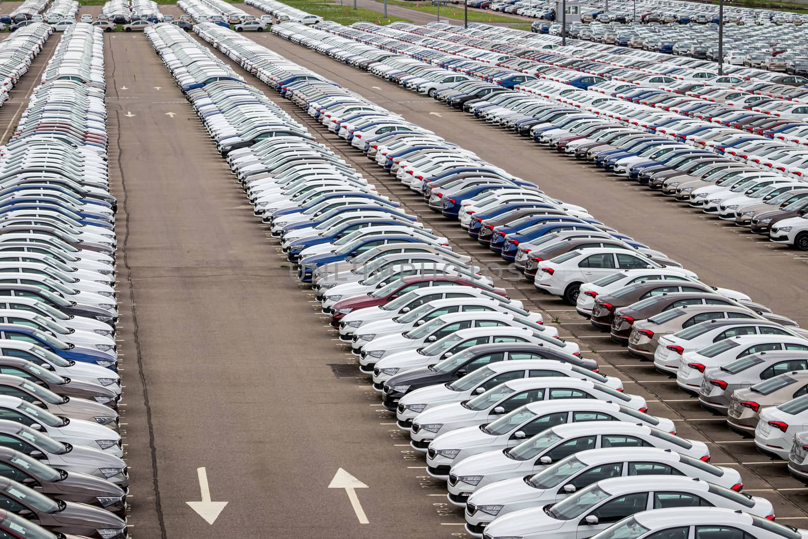 Rows of a new cars parked in a distribution center of a car factory. Top view to the parking in the open air.