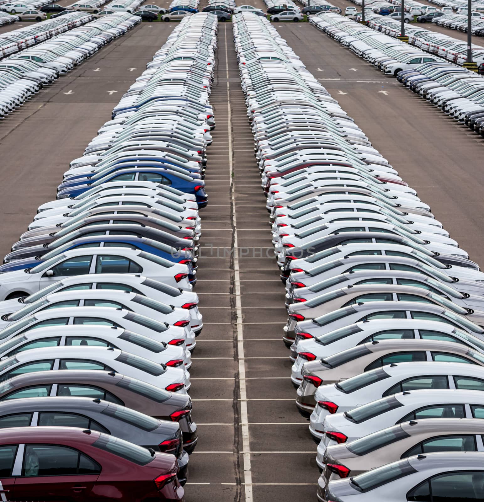 Rows of a new cars parked in a distribution center of a car factory. Top view to the parking in the open air. by Eugene_Yemelyanov