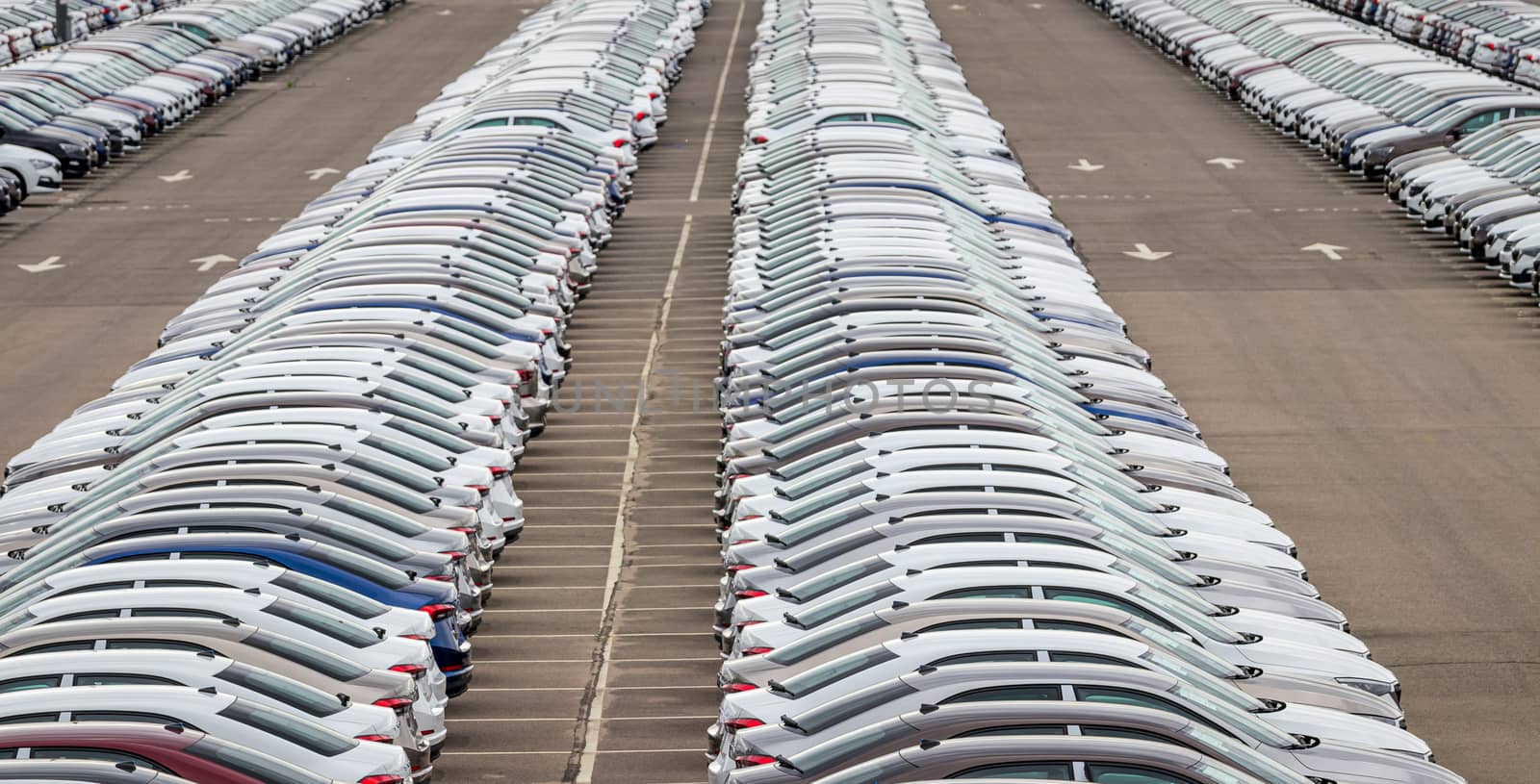 Rows of a new cars parked in a distribution center of a car factory. Top view to the parking in the open air. by Eugene_Yemelyanov