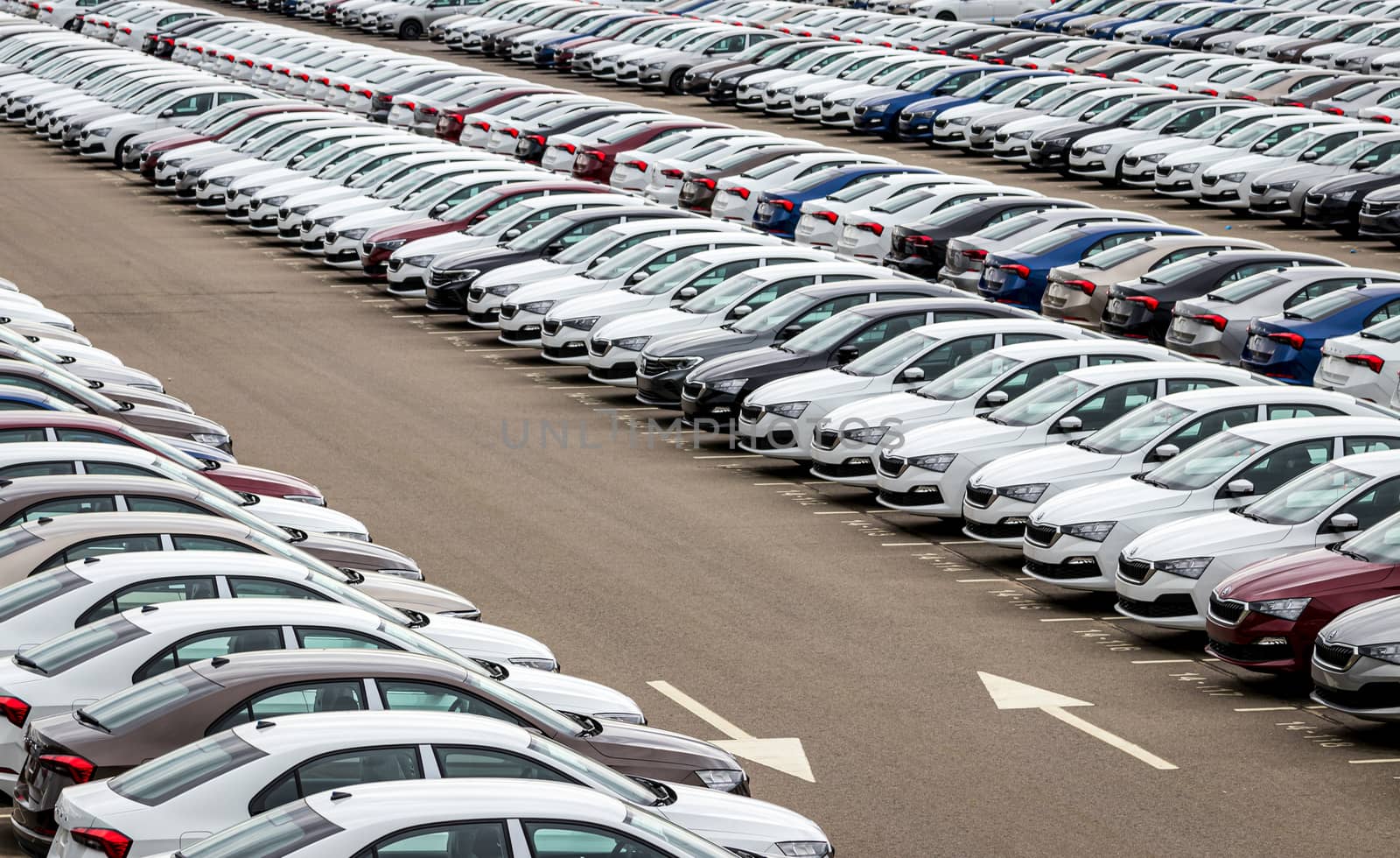 Rows of a new cars parked in a distribution center of a car factory. Top view to the parking in the open air. by Eugene_Yemelyanov