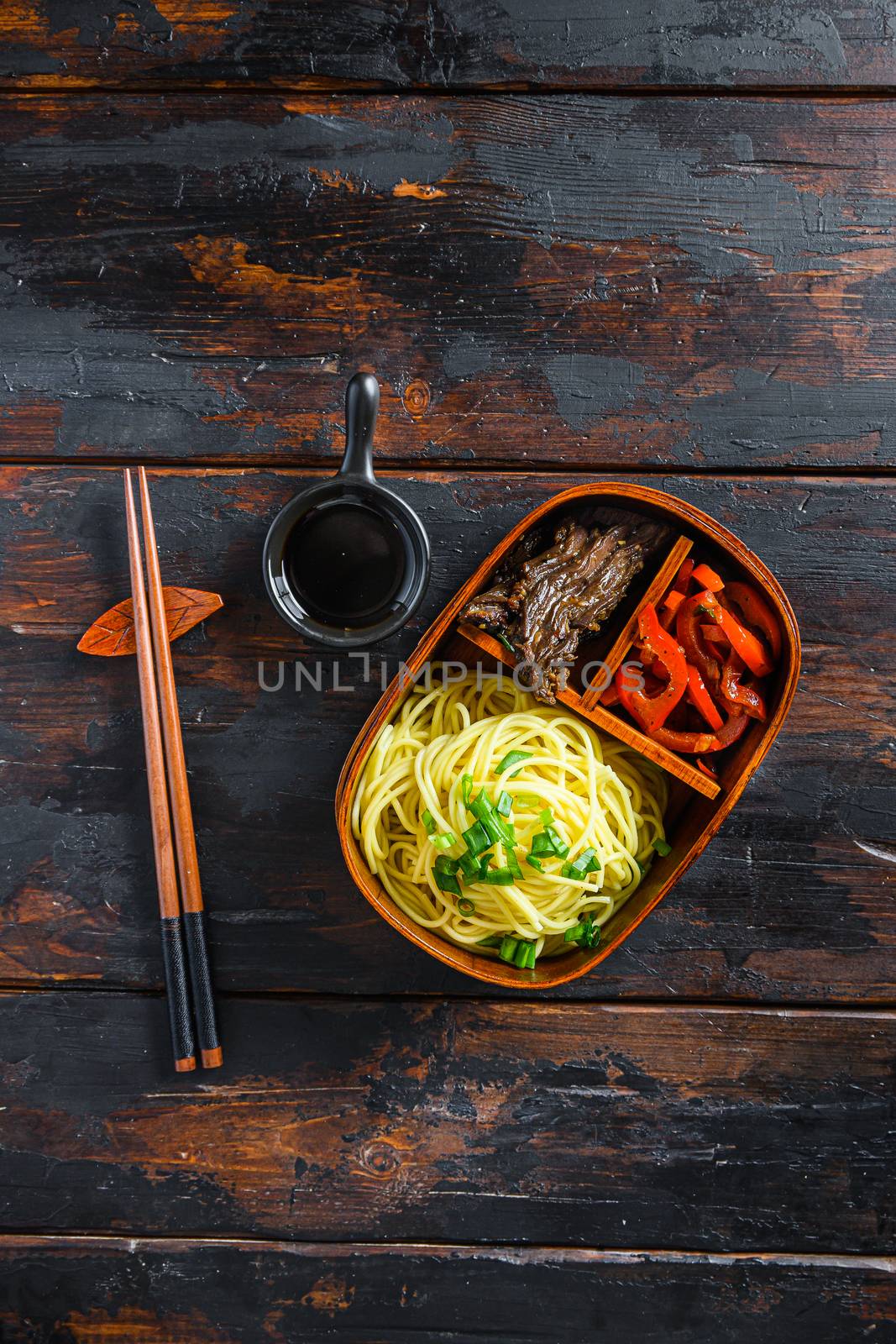 Homemade Bento pack lunch, grilled beef and noodles with ingredients top view dark wooden table