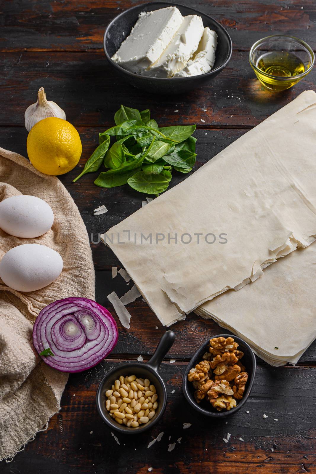 Greek spanakopita ingredients filo spinach eggs feta side view on dark wooden background by Ilianesolenyi