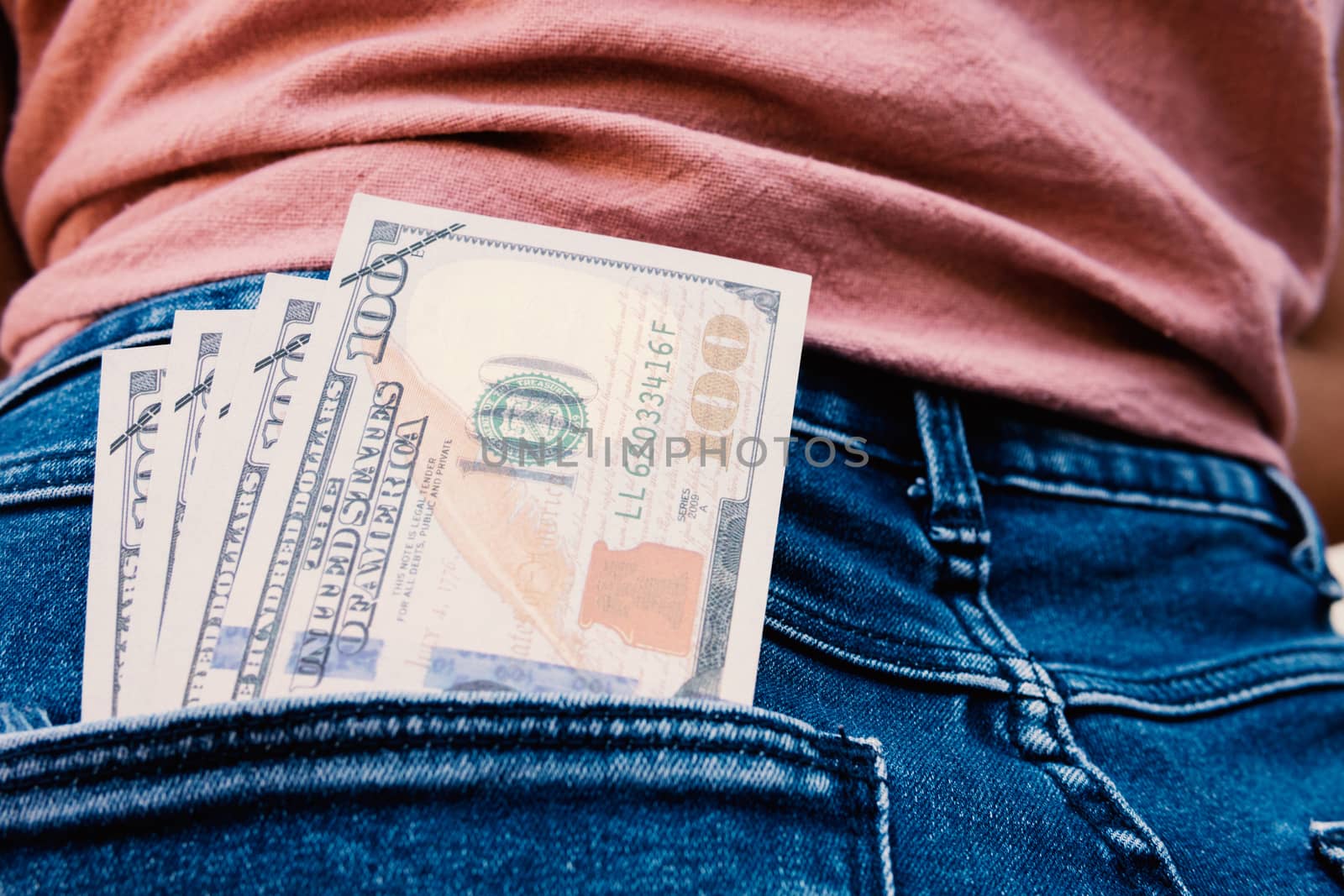 Many dollar 100 banknotes in a woman's rear jean pocket