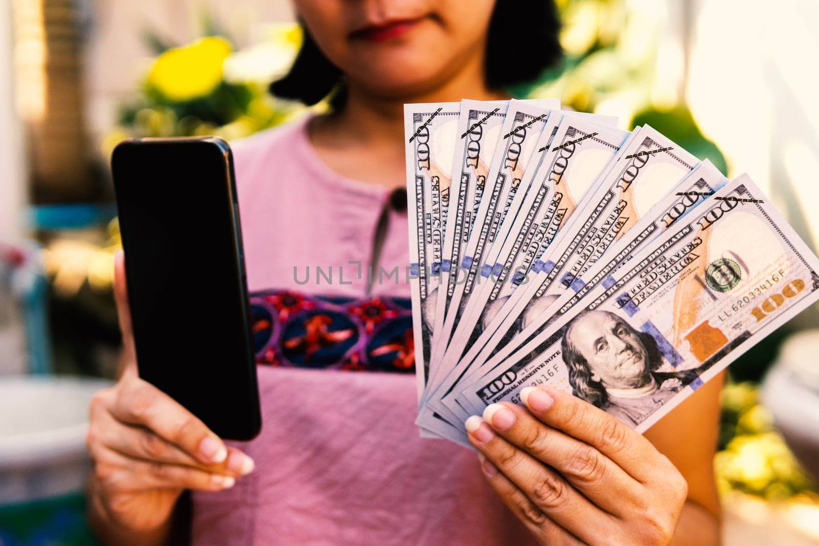 Women show hundreds of dollars of banknotes and smartphones.