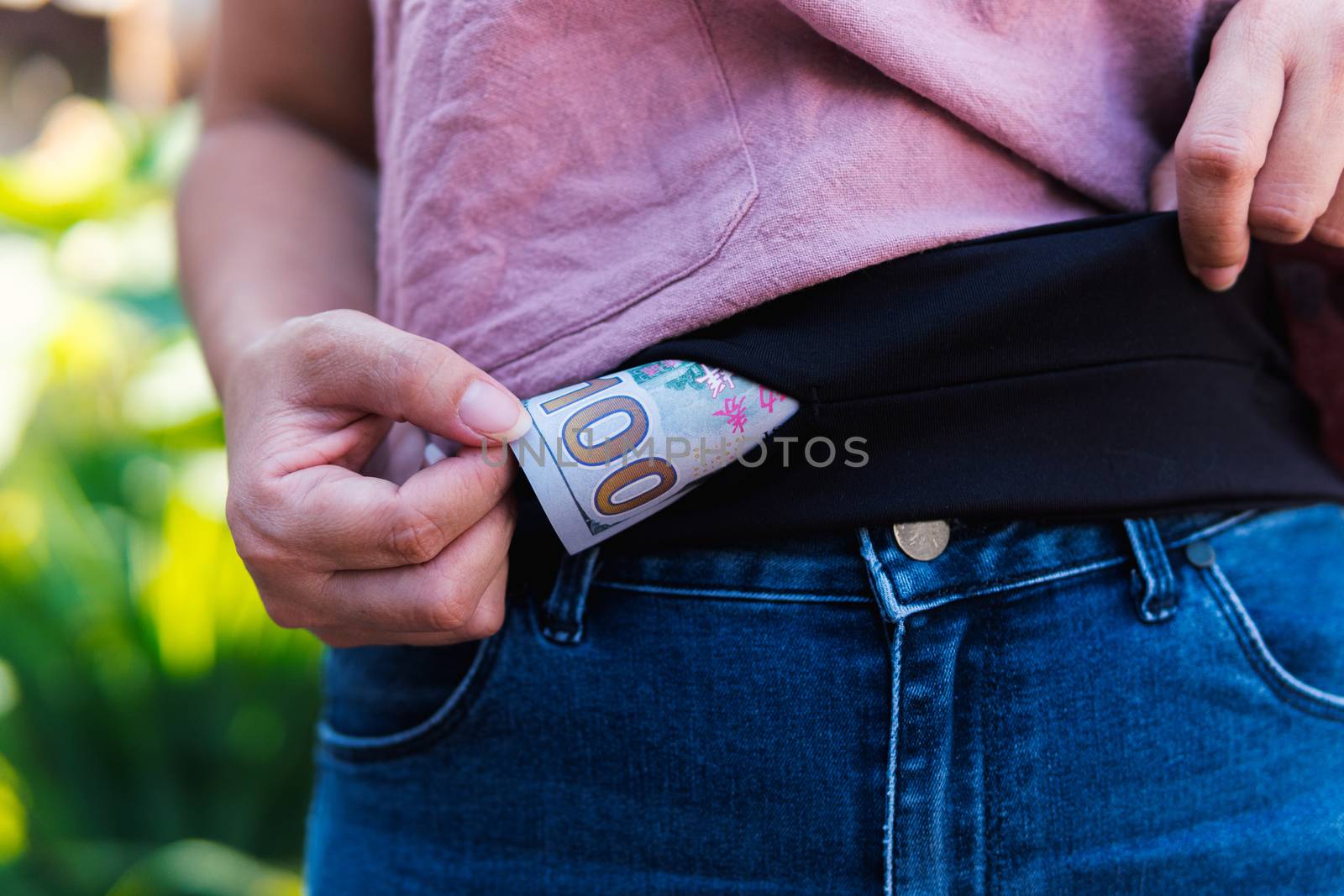 Asian woman is picking up a 100 bank note from a secret purse.