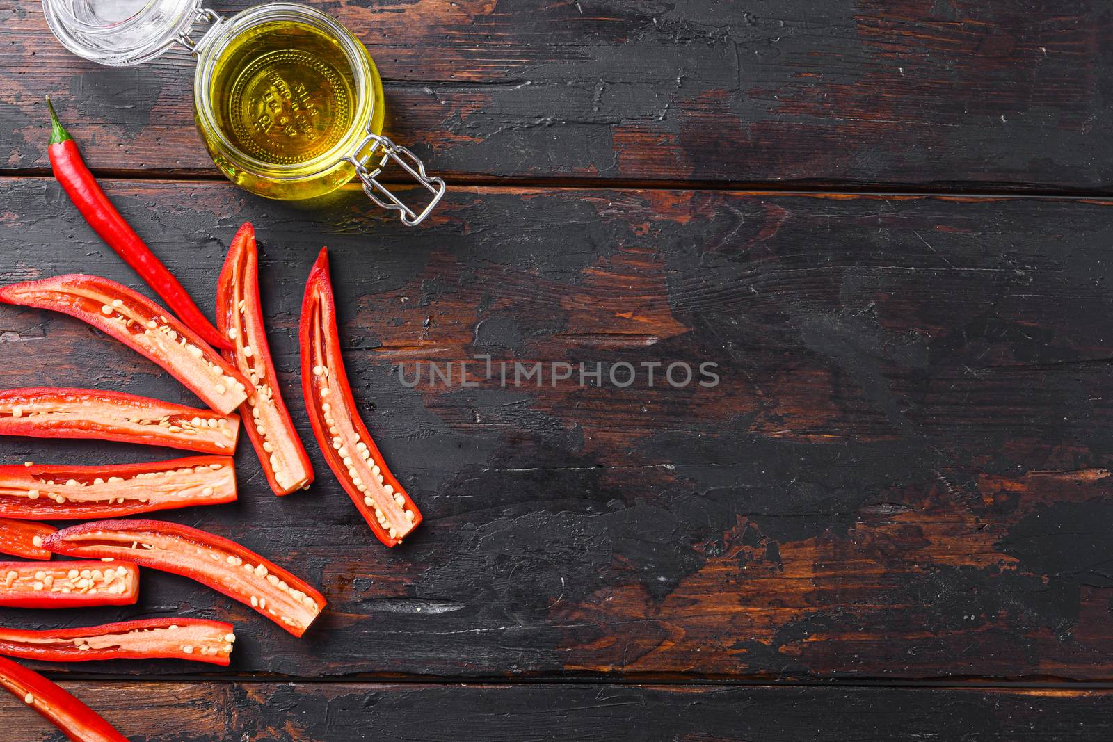 Ripe chili pepper sliced for making spicy olive oil over old dark wooden table top view space for text
