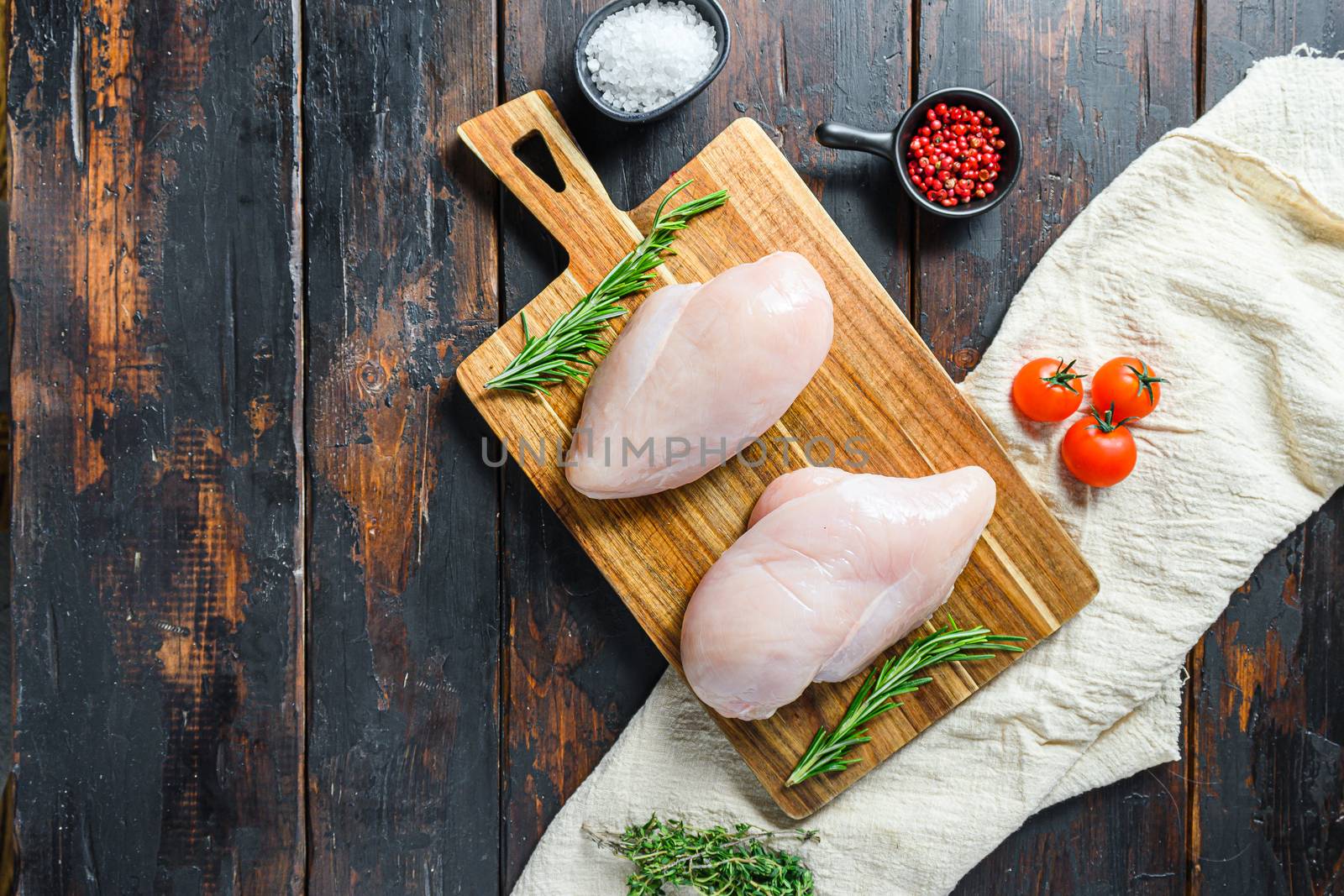 Raw chicken breast fillets and vegetable on chopping board overdark wooden background top view space for text