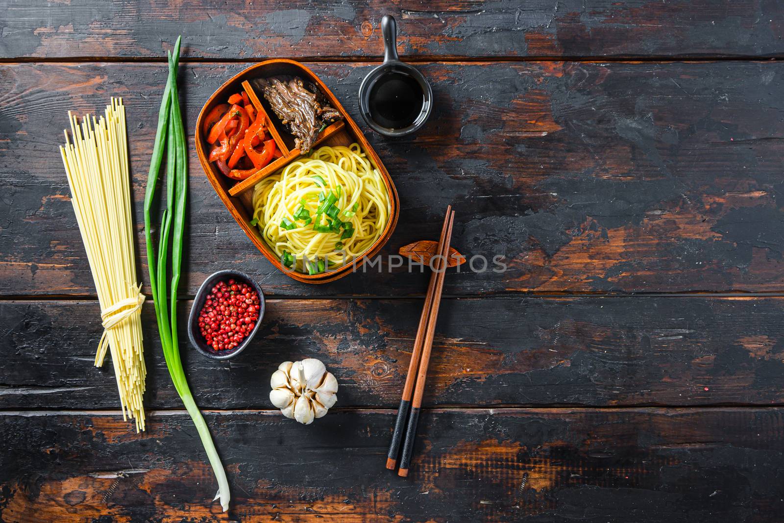 Homemade Bento pack lunch, grilled beef and noodles with ingredients top view dark wooden table space for text