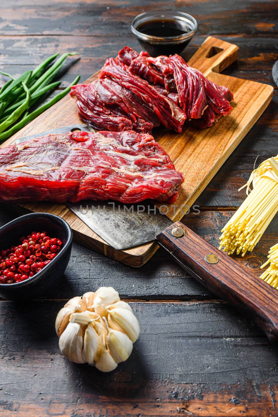 Chinese noodles with vegetables, . Machete steak and butcher cleaver over wooden background. Side view. by Ilianesolenyi