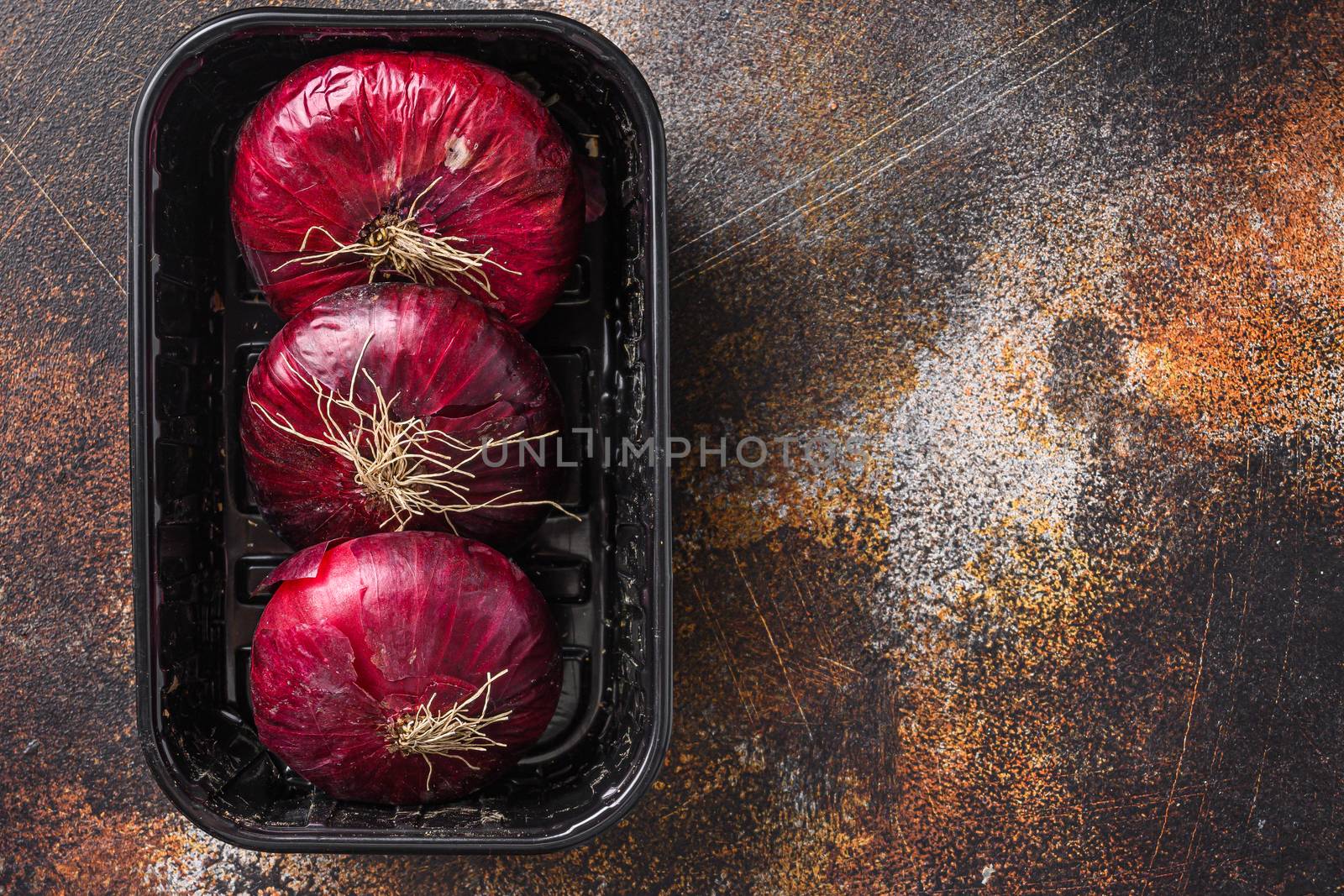 Farm red onions in tray on old oak wooden table