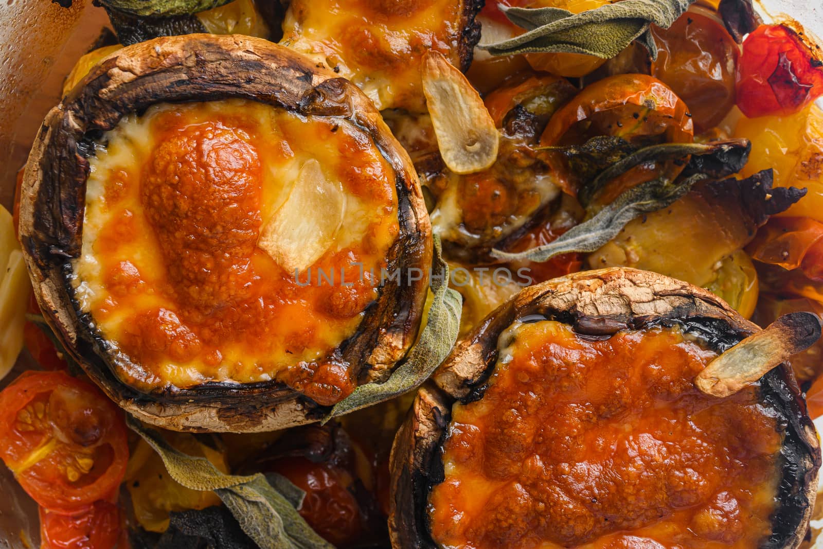 Portobello baked with cheddar cheese, cherry tomatoes and sage in glass pot on white concrete background top view close up