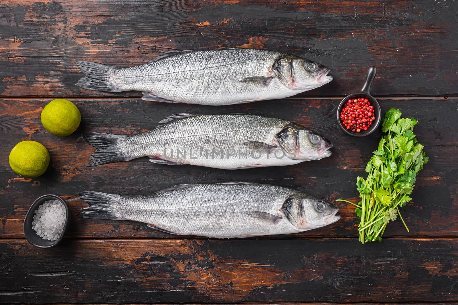 Seabass with spices and herbs ingredients on old fisherman dark wooden table top view.