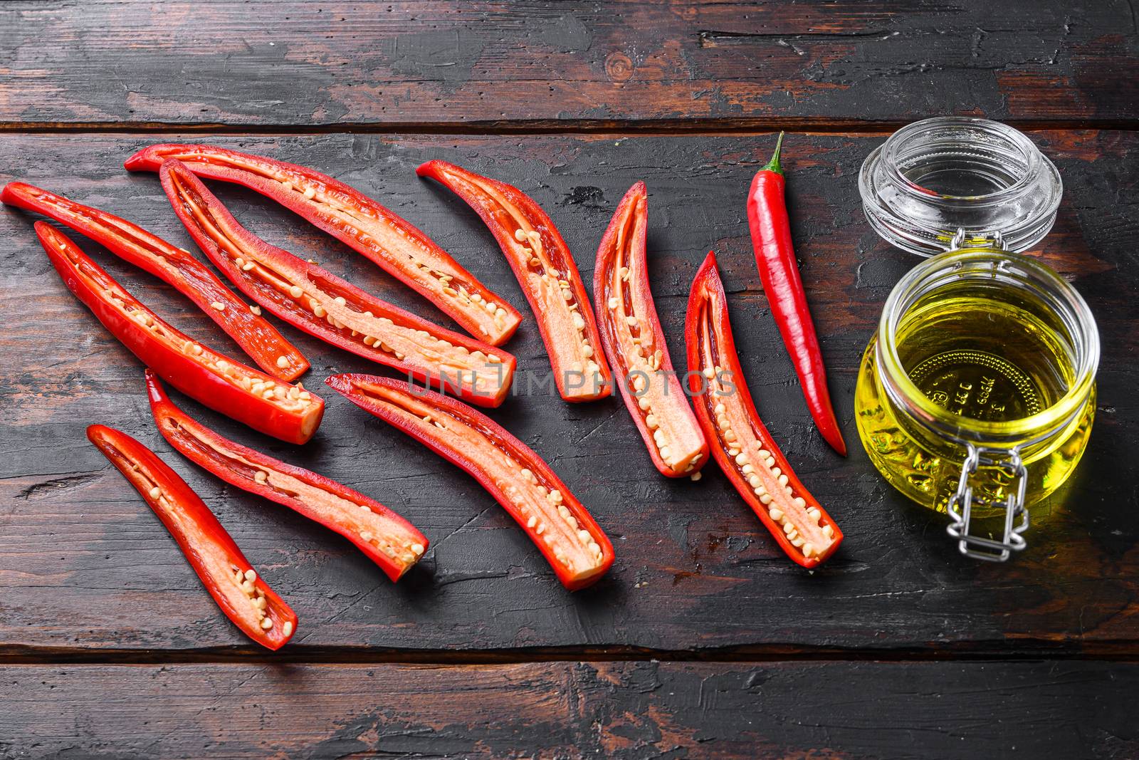 Red Hot Chili Peppers sliced for making spicy olive oil over old dark wooden table side view