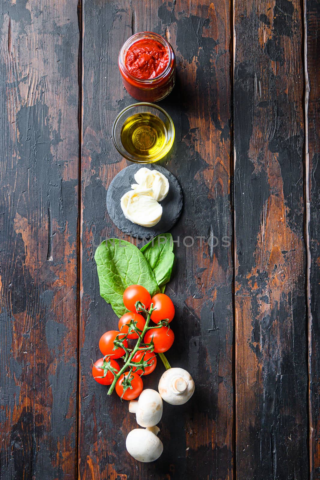 Raw pizza ingredients for cooking, tomatoes, oil, garlic, basil, sauce, mushroom on wood background by Ilianesolenyi