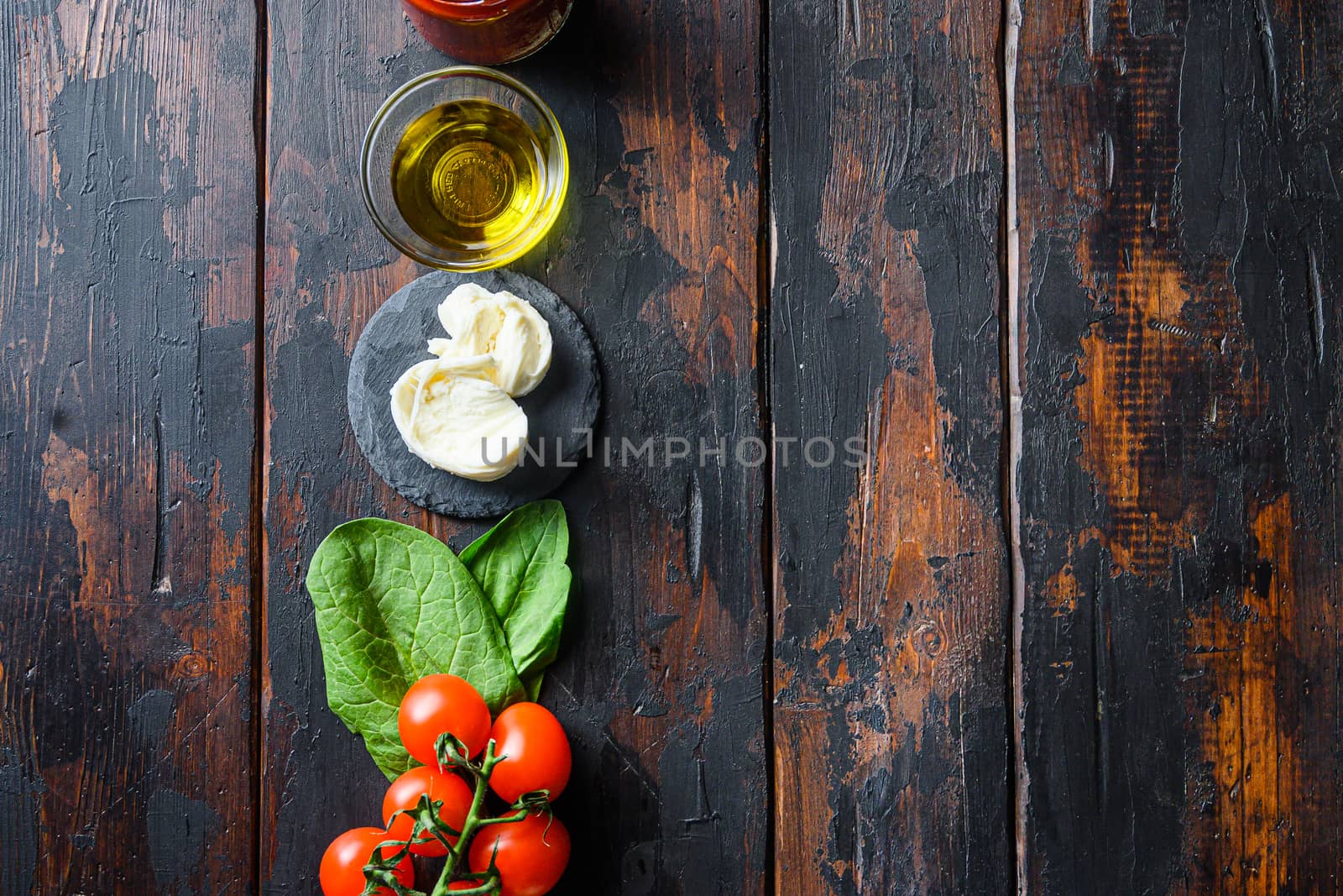 Pizza ingredients for cooking, tomatoes, oil, garlic, basil, sauce, mushroom on wood background.