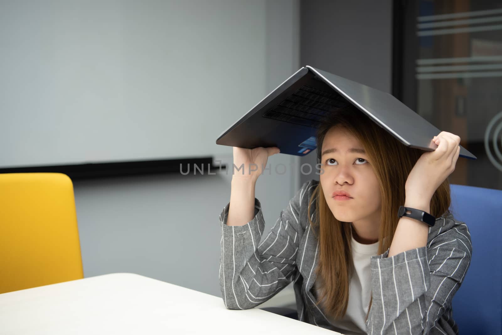 Asian woman is student,businesswoman working by computer notebook, laptop in office meeting room with whiteboard background with annoyed, displeased emotion in concept working woman,unhappy in life