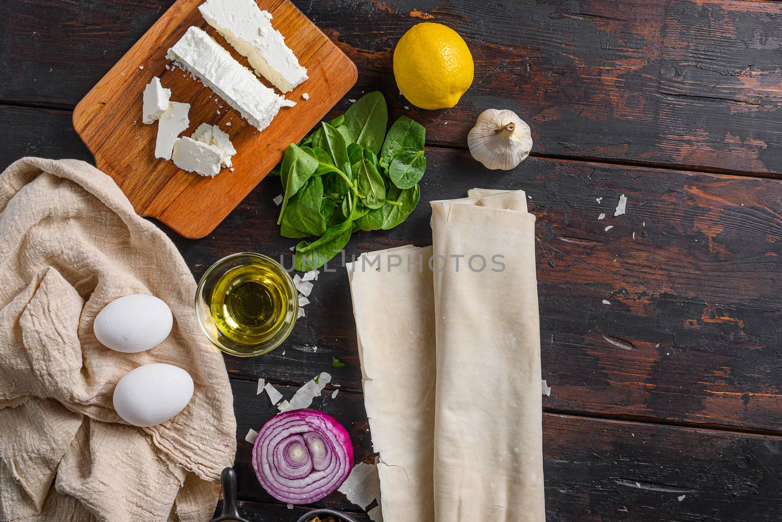 Greek spanakopita ingredients filo spinach eggs feta top view on dark wooden background space for text