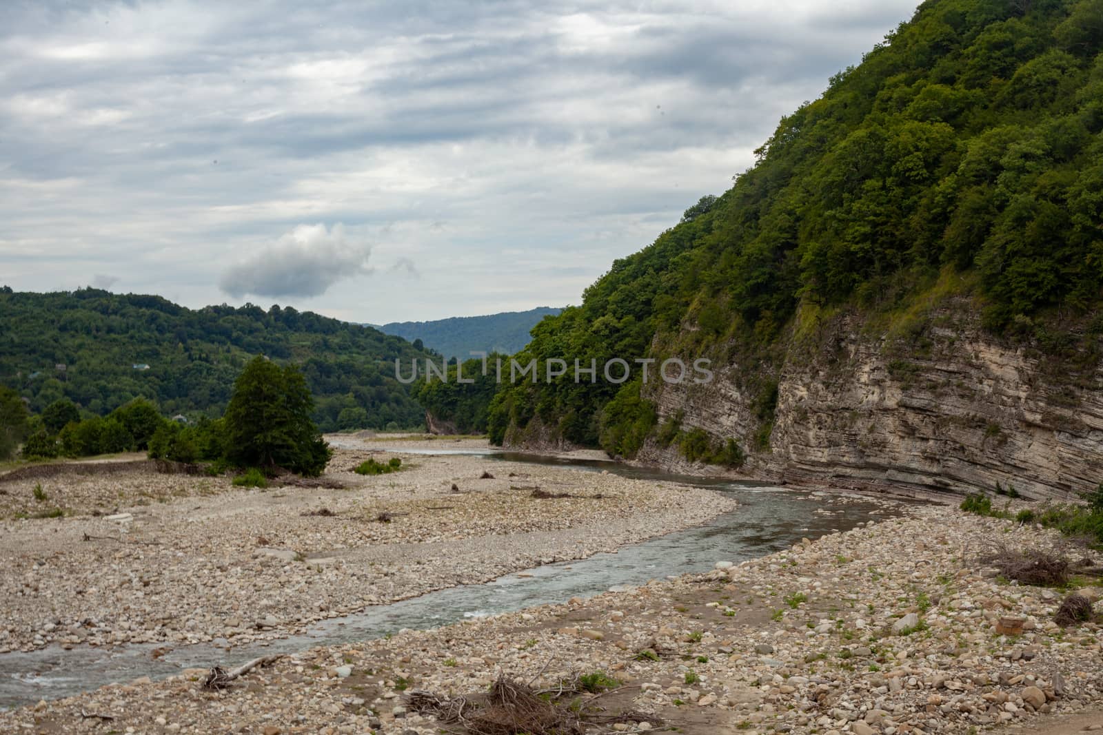 Cloudy summer landscape with a stone bed of the Ashe river