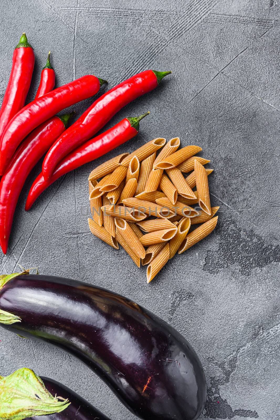 Penne pasta ingredients eggplant pasta, pepper tomatoe sauce, on grey background side view. by Ilianesolenyi