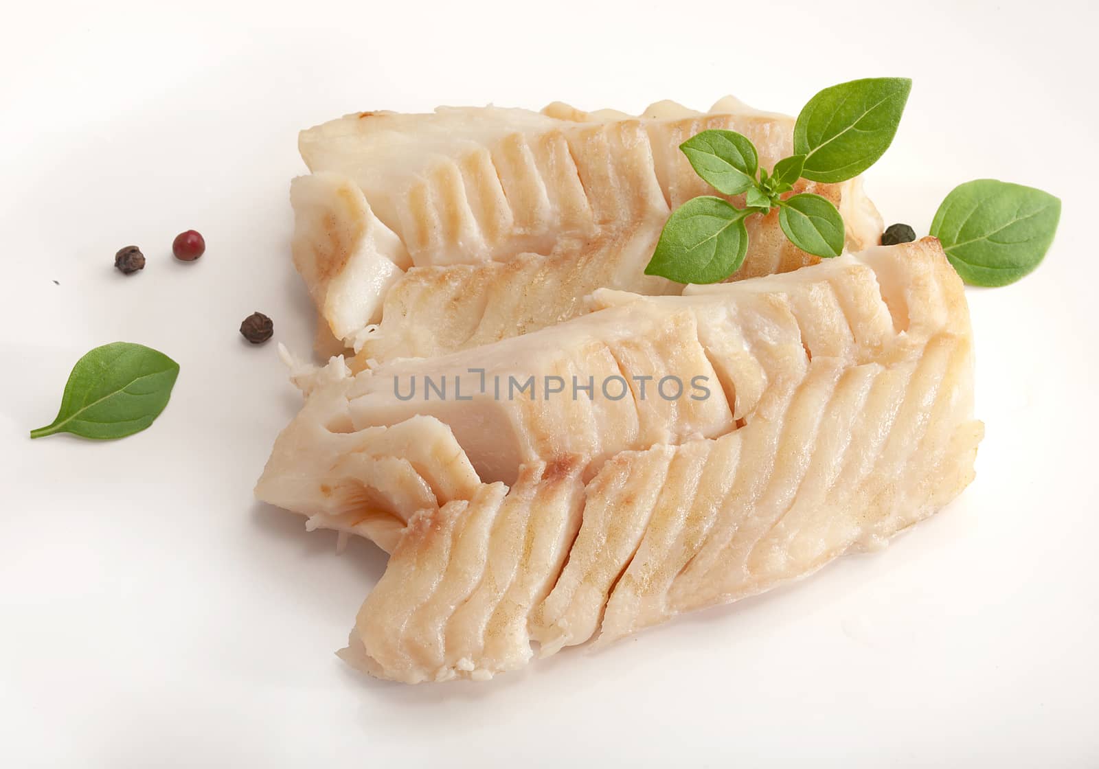 Two baked cod loin pieces with fresh green basil
