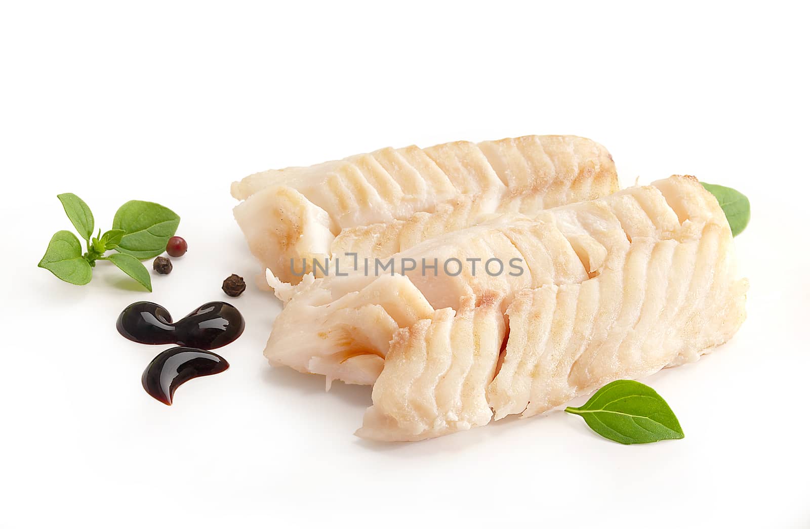 Two pieces of baked cod loin with basil, sauce and black pepper