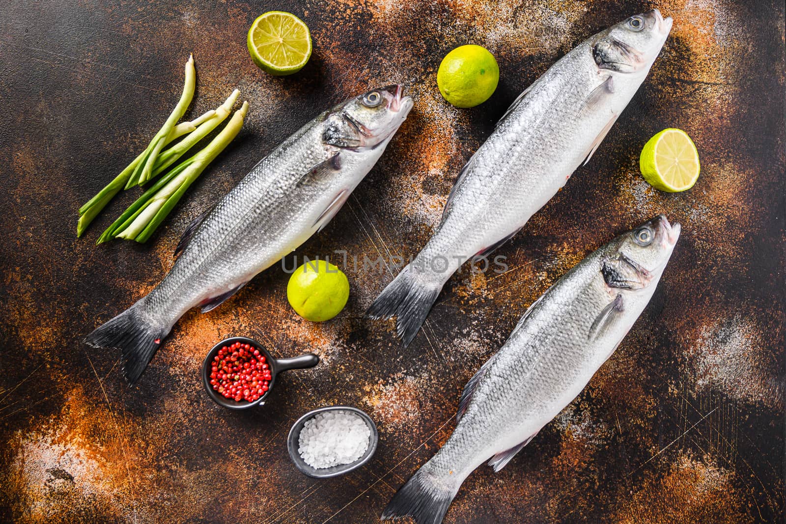 Set of sea bass with spices and herbs ingredients over darc rustic background top view