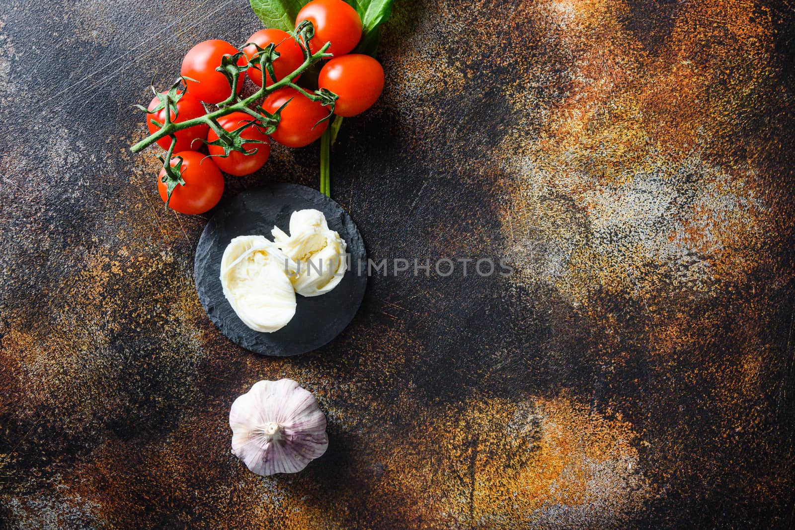 Raw pizza ingredients for cooking, tomatoes, oil, garlic, basil, sauce, mushroom on dark background.