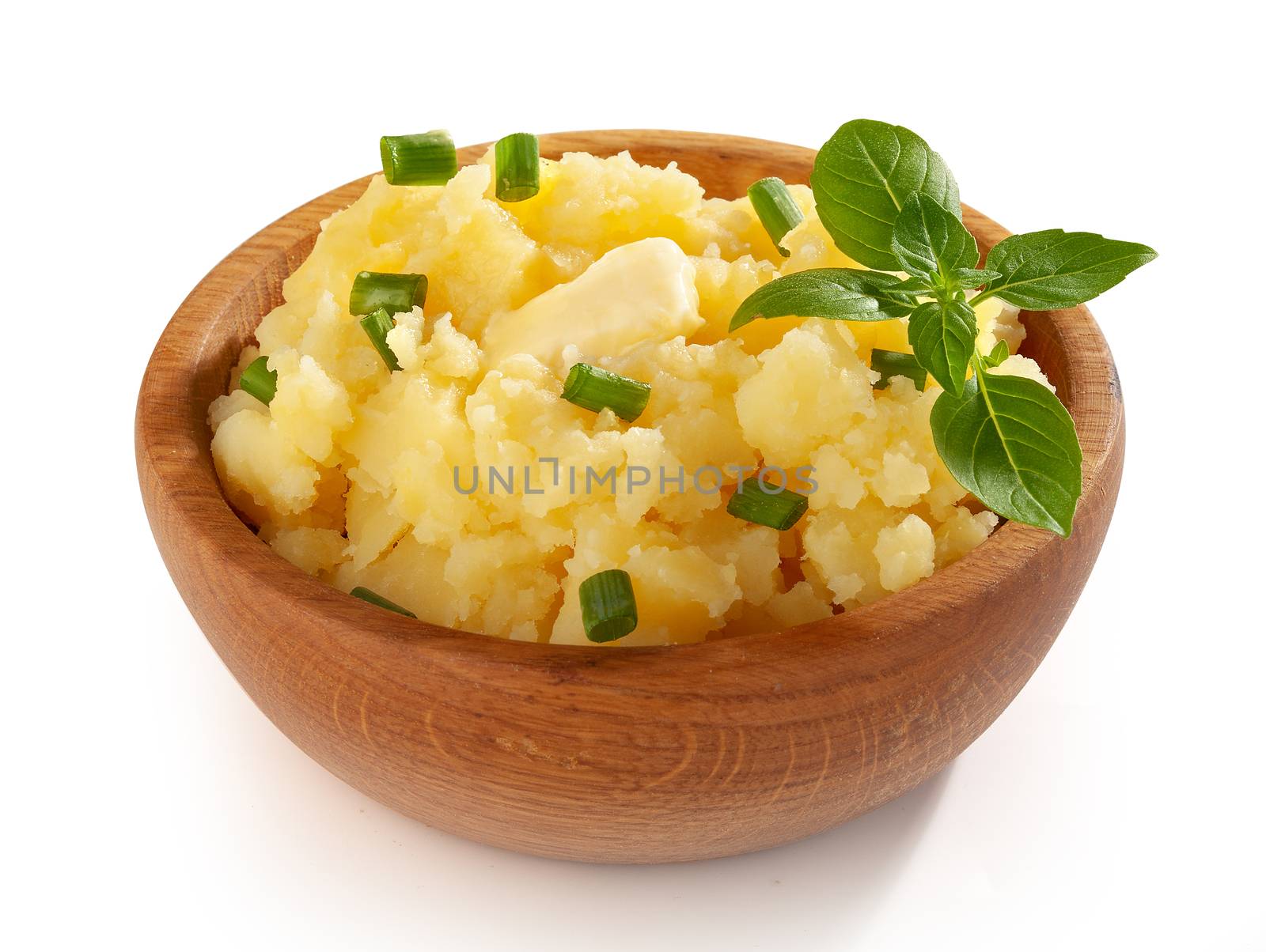 Mashed potatoes with butter, fresh basil and greein onion in the wooden bowl