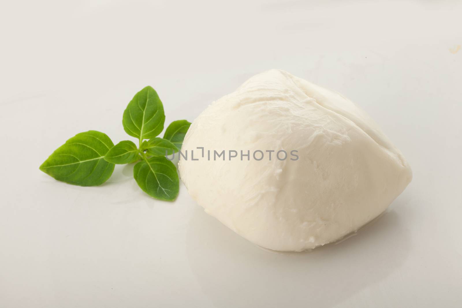 Whole ball of mozzarella with fresh greeen basil leaves