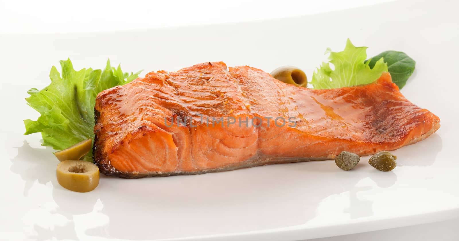 Baked fillet of trout with green lettuce and basil on the plate