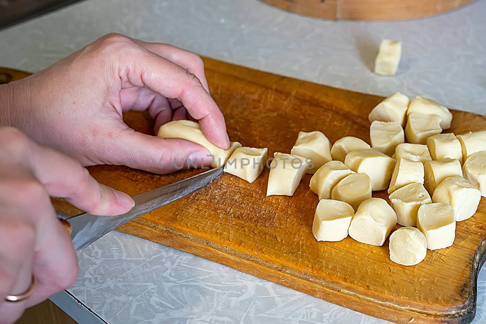 cook slices dough into pieces on a wooden board