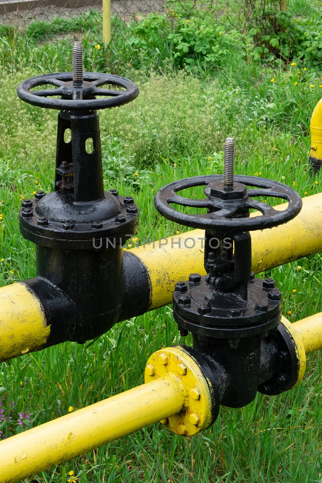 two massive black valves on a yellow gas pipe