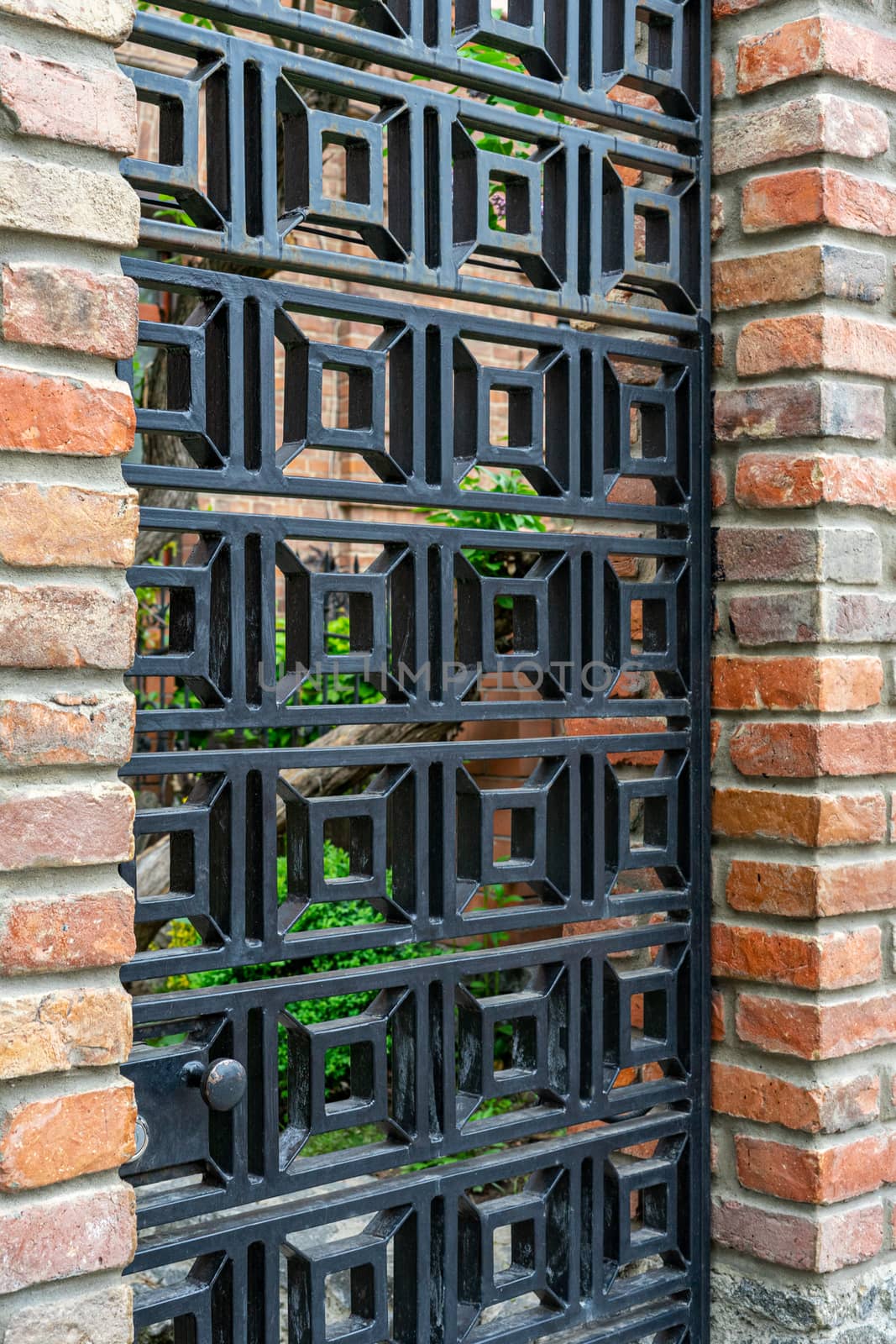 metal wrought iron door lattice in a red brick fence