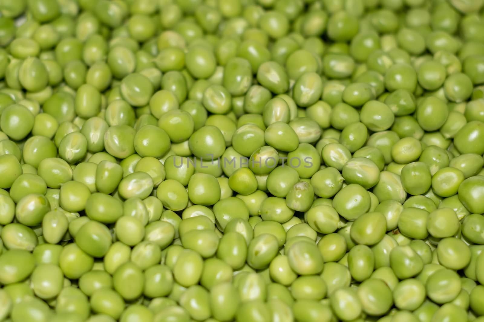 Background of young juicy green peeled peas mound               