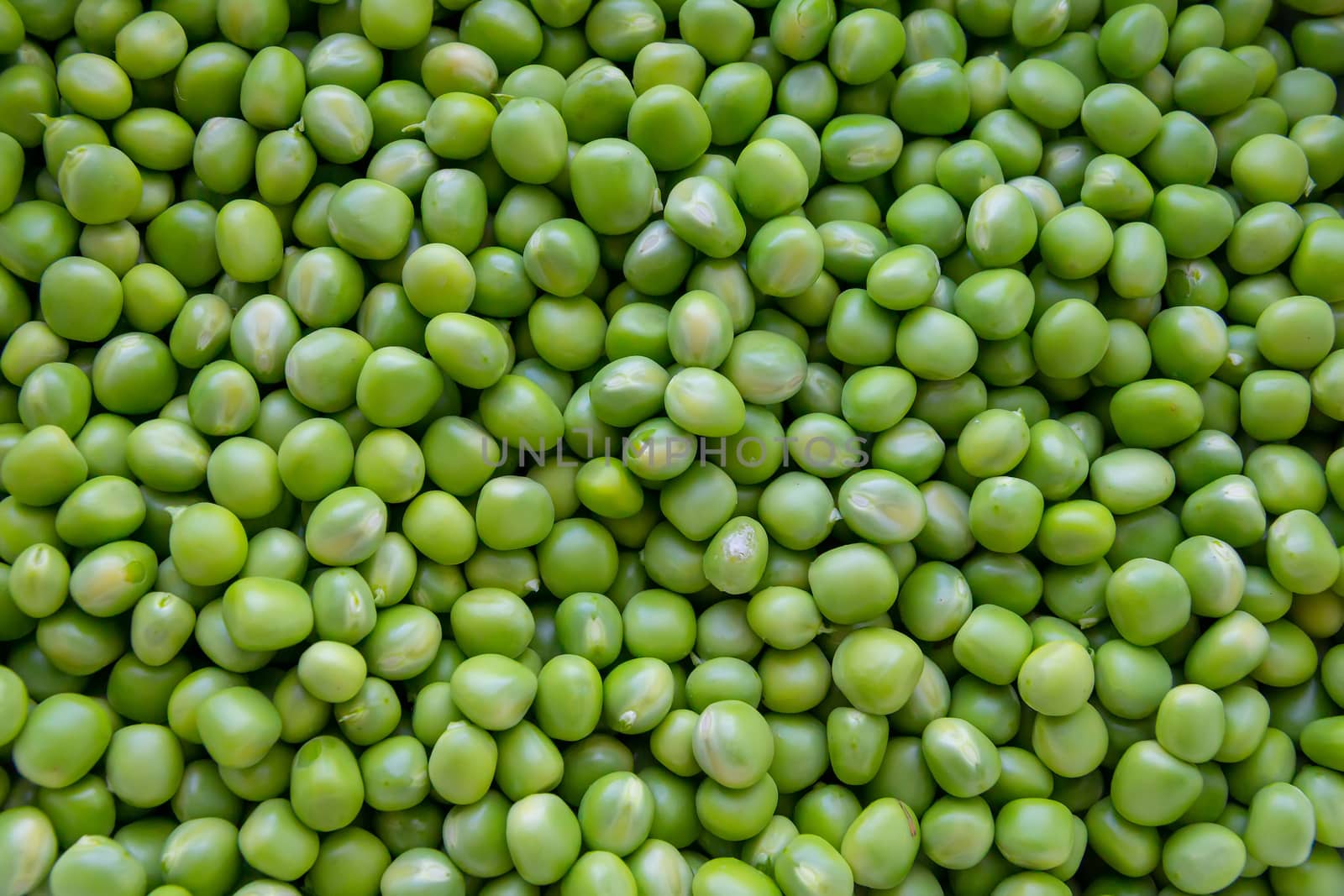 Background of young juicy green peeled peas mound