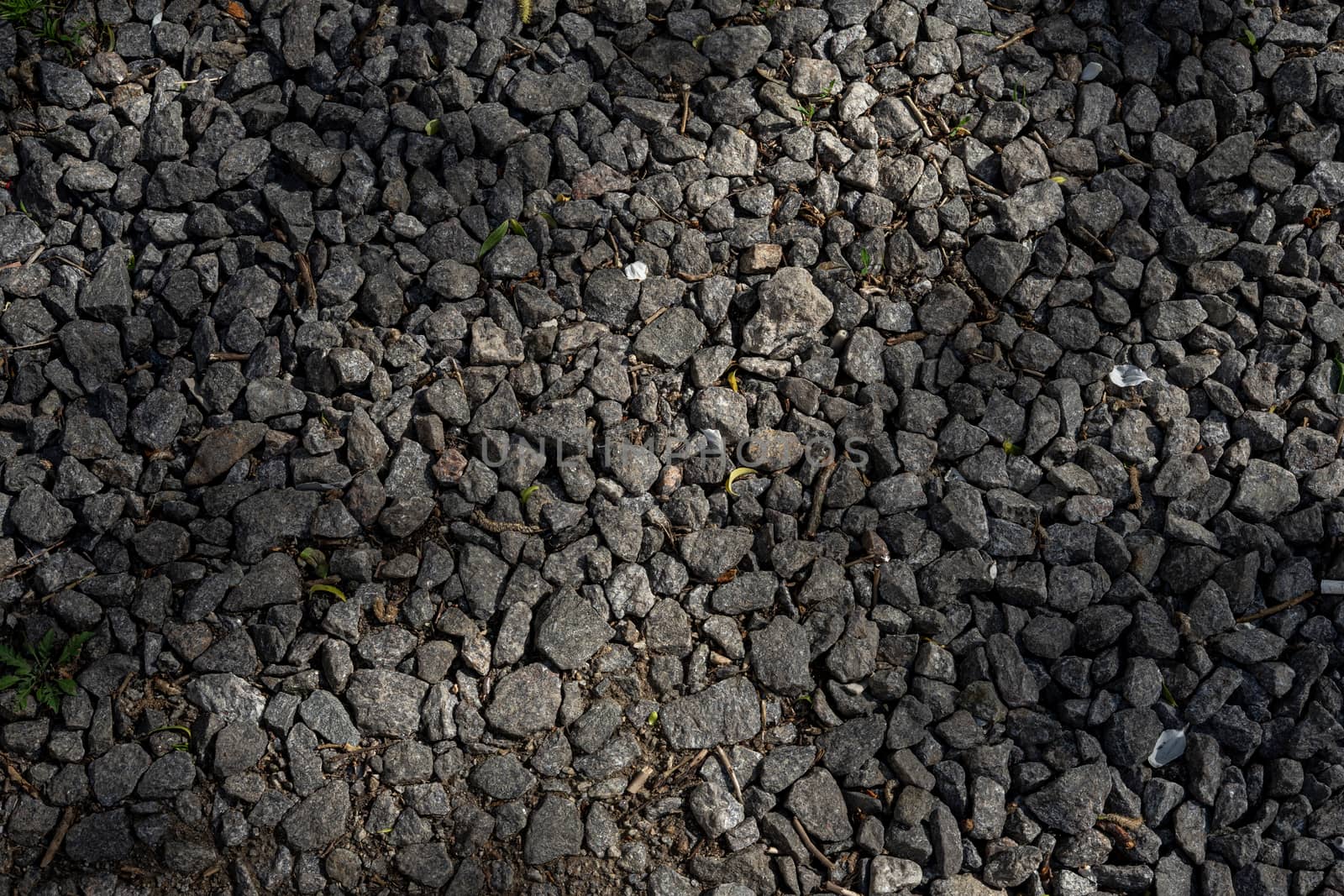 Large compacted rubble lies on the road . Dark brown rubble . Macadam