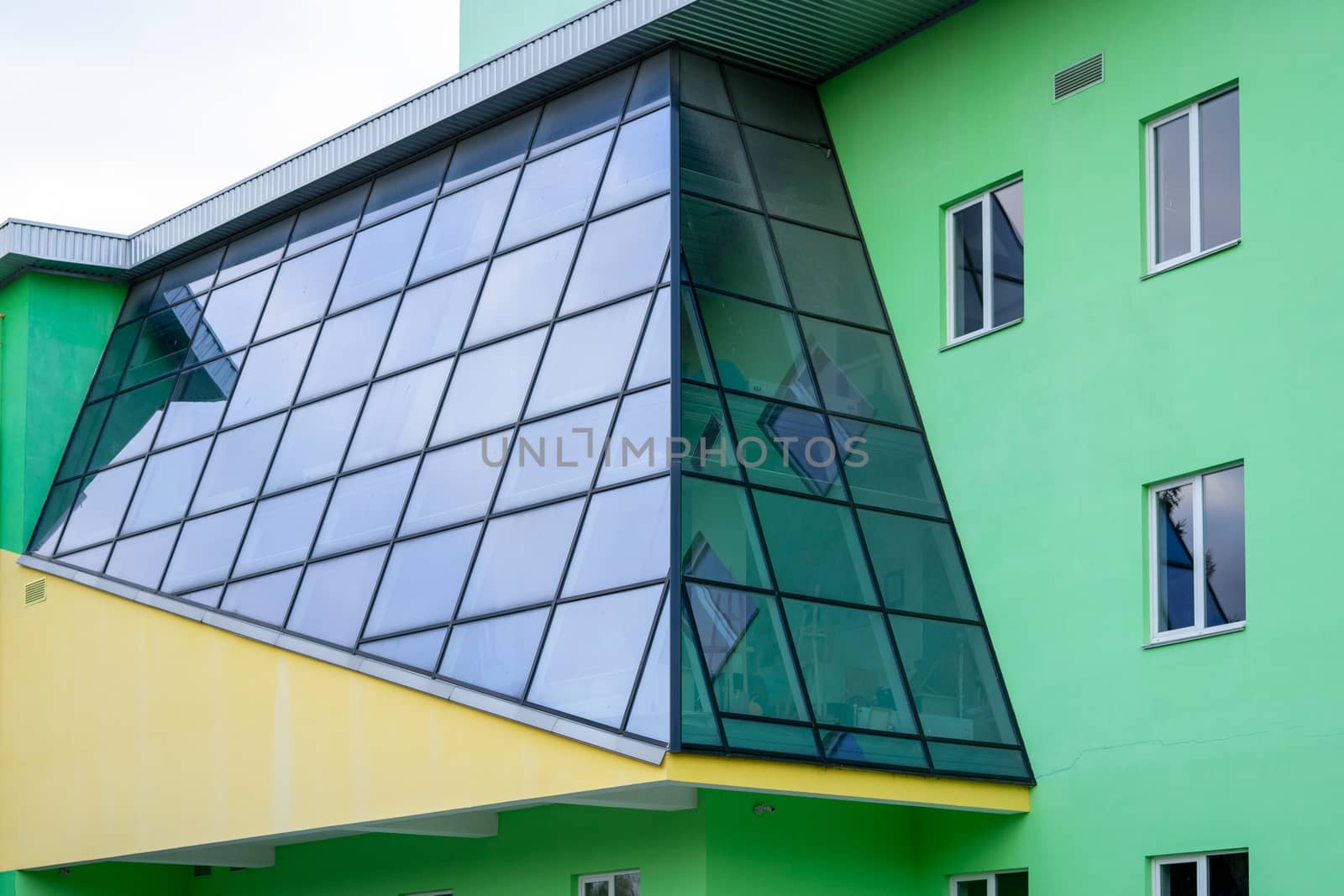 Modern house with a glass wall. The house is painted green. City architecture