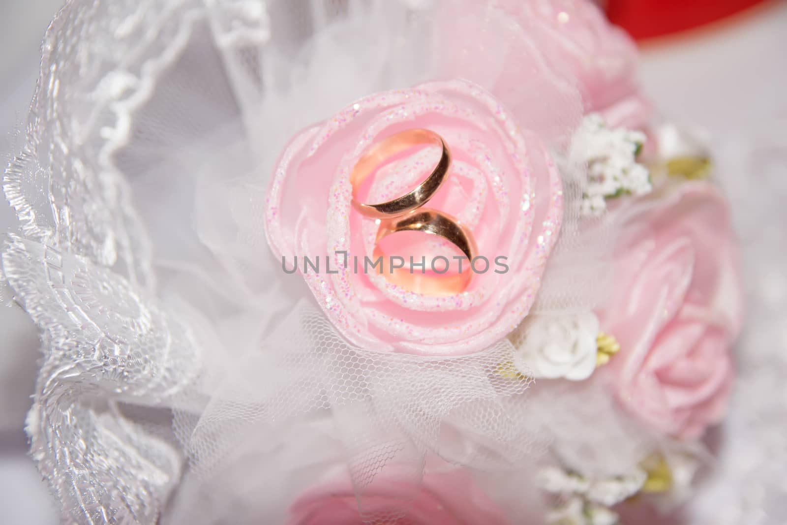 Golden wedding rings on a pink rose