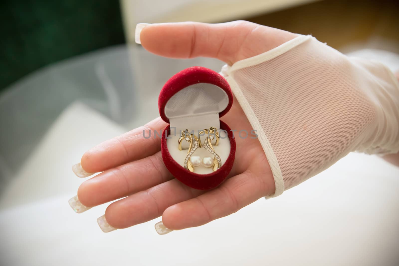 The bride holds a box of gold earrings in her hand. Red box with earrings by Serhii_Voroshchuk