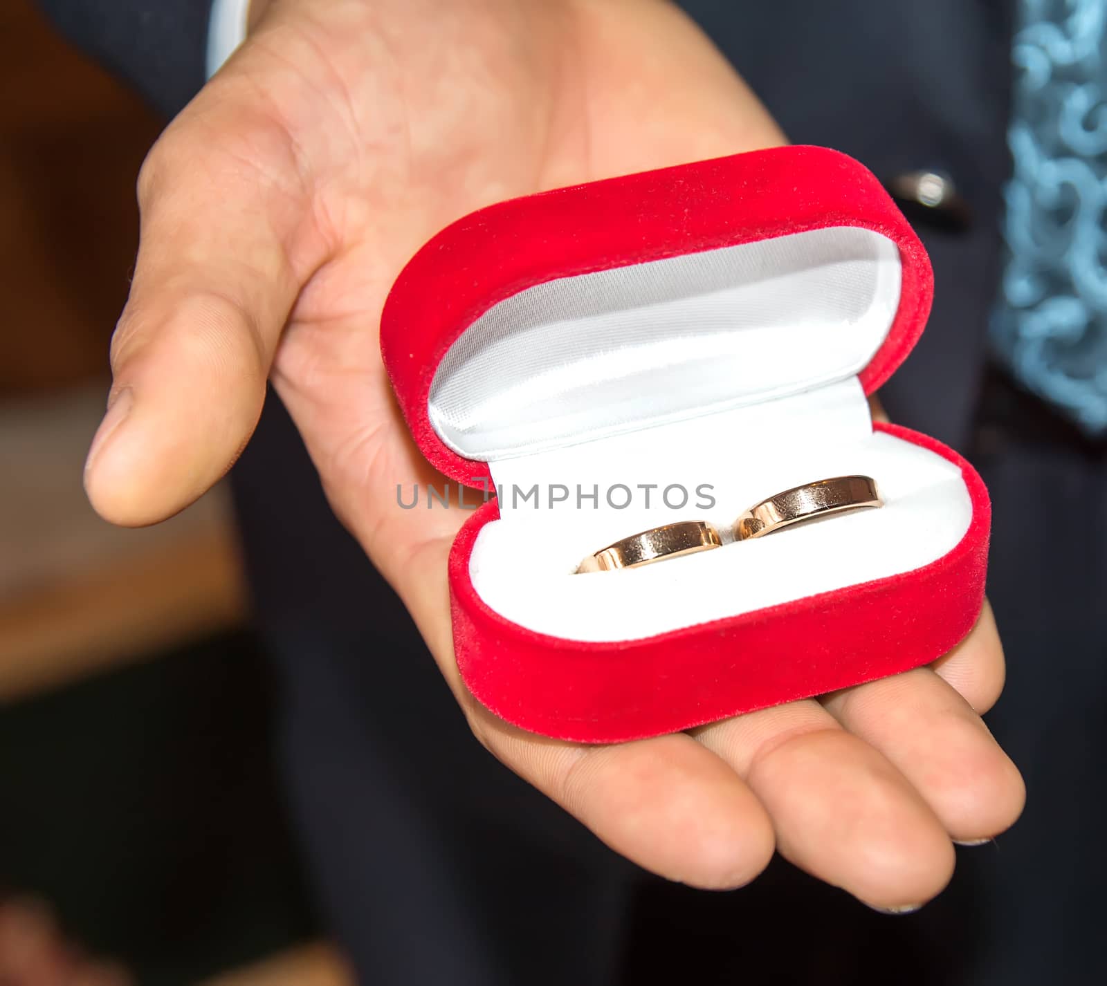 The groom holds a red box with wedding rings. Close up by Serhii_Voroshchuk