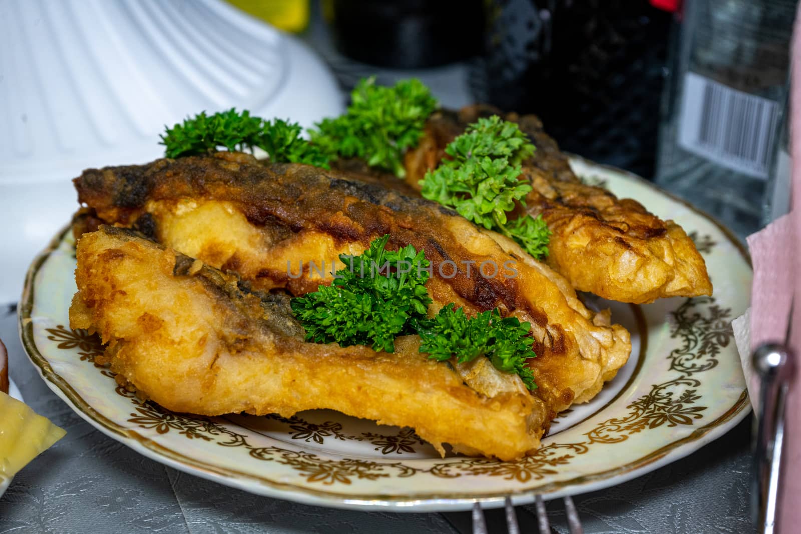 Golden fried fish decorated with parsley. Fried fish on a plate by Serhii_Voroshchuk