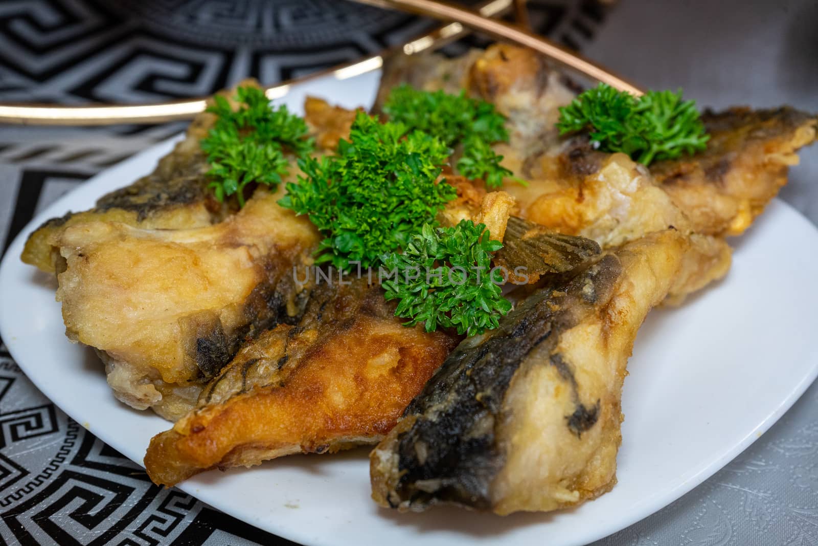 Golden fried fish decorated with parsley. Fried fish on a plate