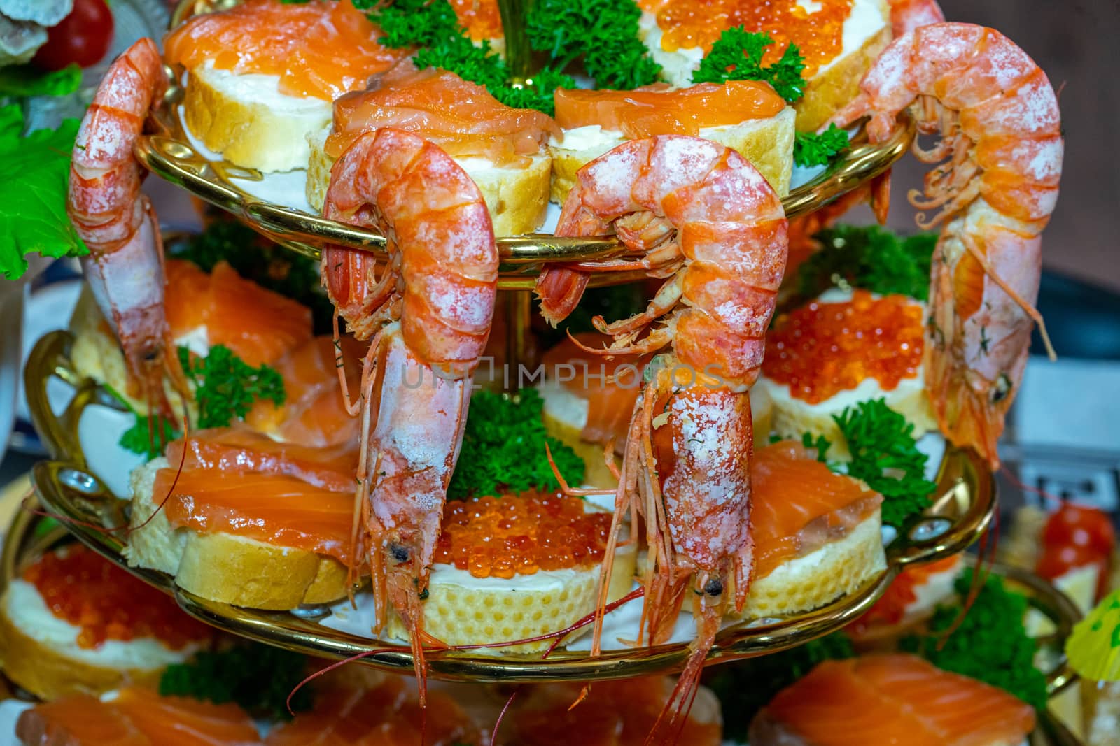 Shrimp and sandwiches with red caviar decorated with greens