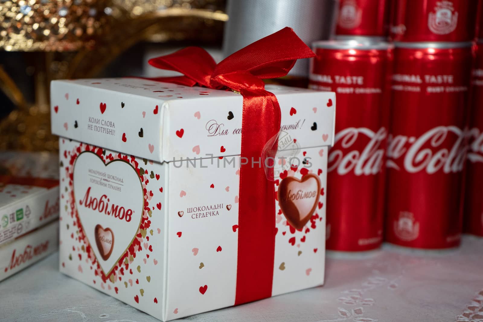 Ukraine, Vinnytsia - May 23, 2020 Gift box with candy tied with a red ribbon and Coca-Cola in the background by Serhii_Voroshchuk