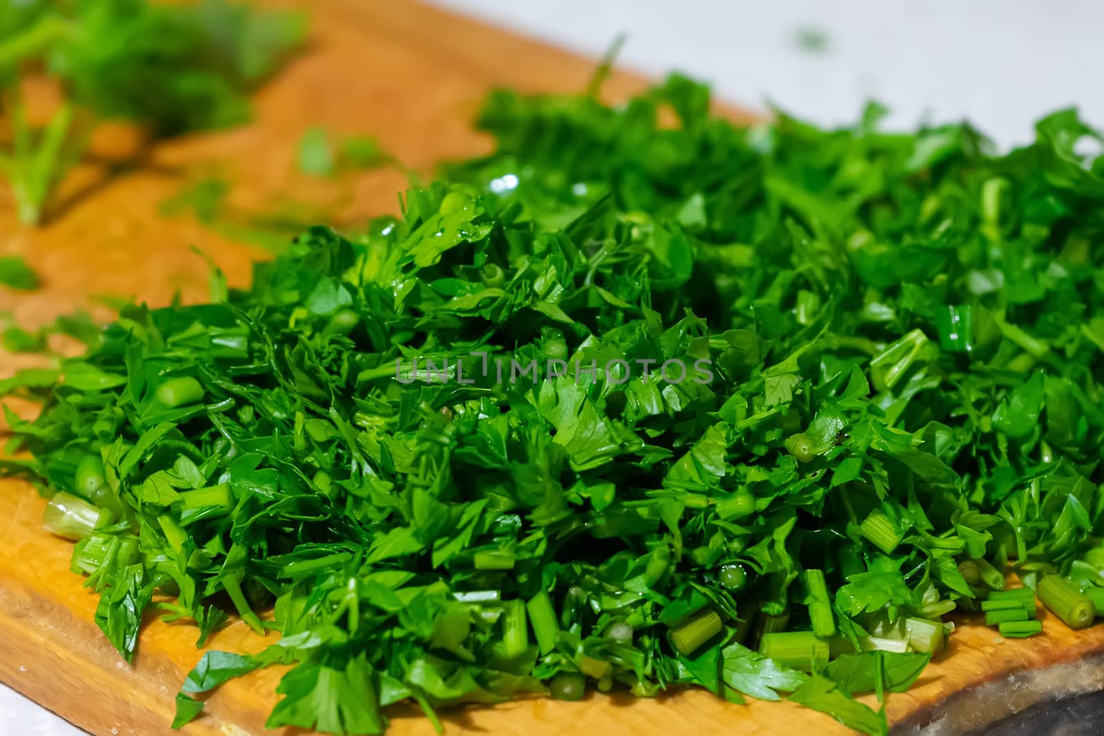parsley greens finely chopped with a knife on a wooden board