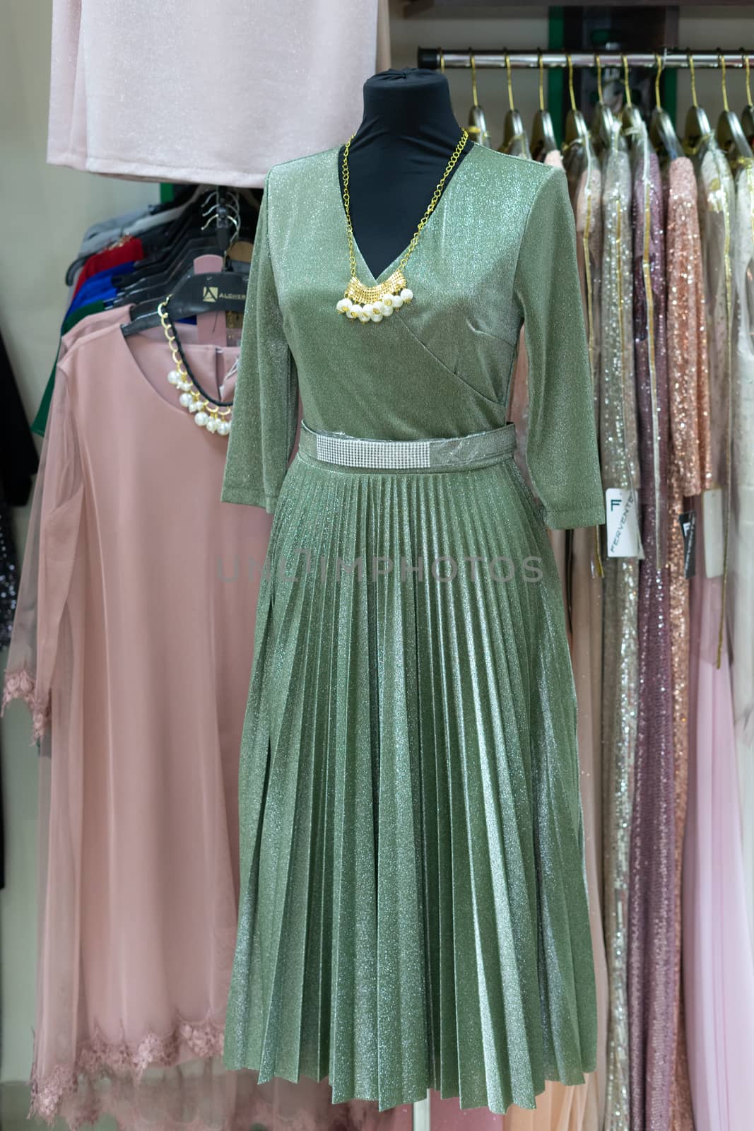 Full length dress. Green dress with a belt hanging on a mannequin. Retail