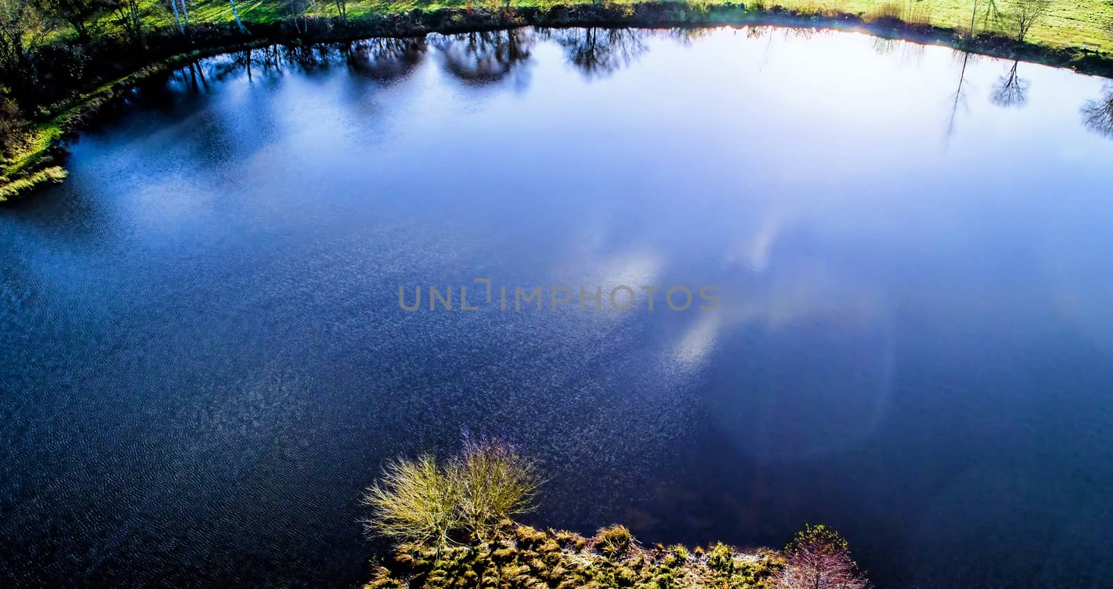 Pond in the back light with the reflections of the sun in the wa by geogif