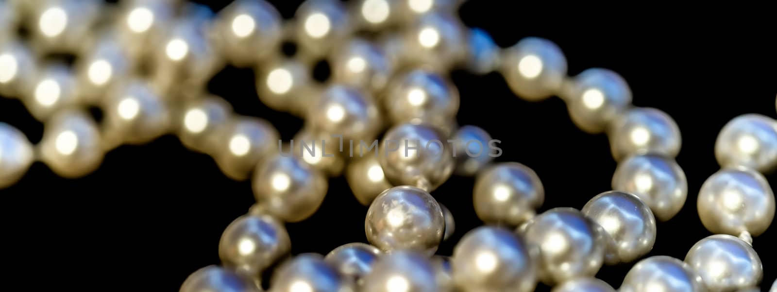 Abstract picture of a pearl necklace, front and back deliberately blurred, black background